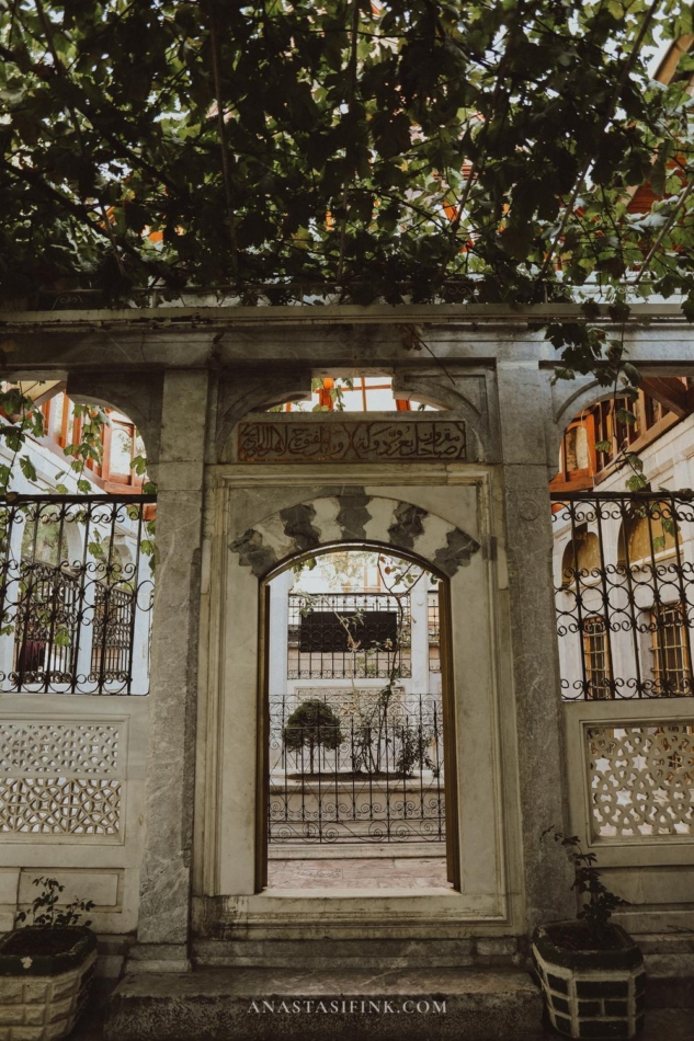 A view through the arched gate of Sadreddin Konevi Mosque, highlighting its beautiful stonework and metal railings.