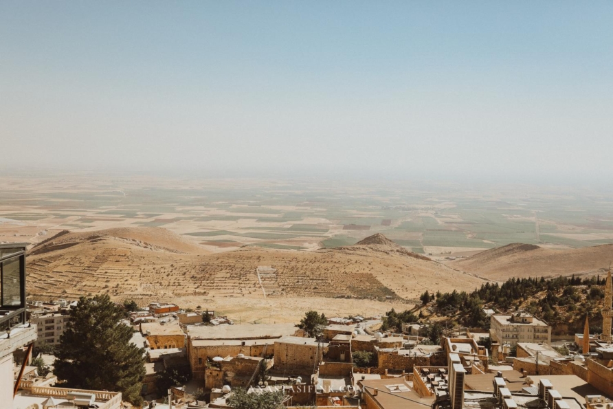 Scenic view of a minaret and dome at sunset in Mardin, overlooking the vast landscape. ​