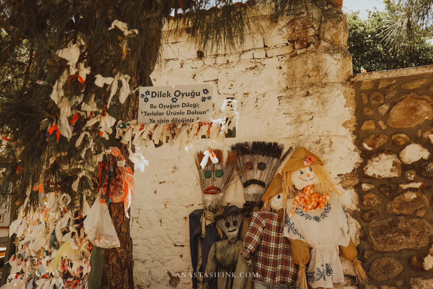 Dilek Oyuğu wish tree with fabric strips and scarecrows nearby