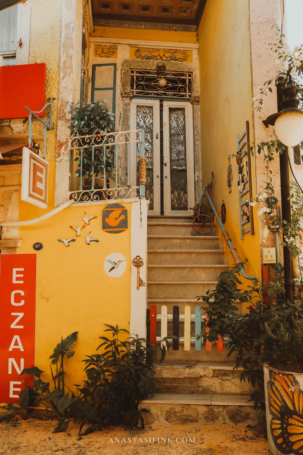 Yellow Eczane pharmacy building with decorated entrance and colorful fence
