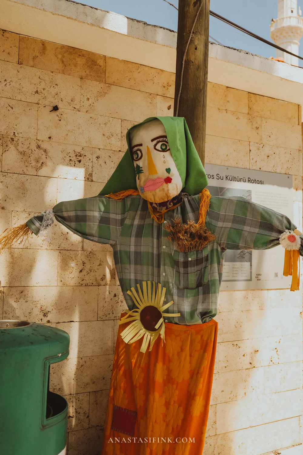 Scarecrow in a green headscarf with a painted face near the mosque