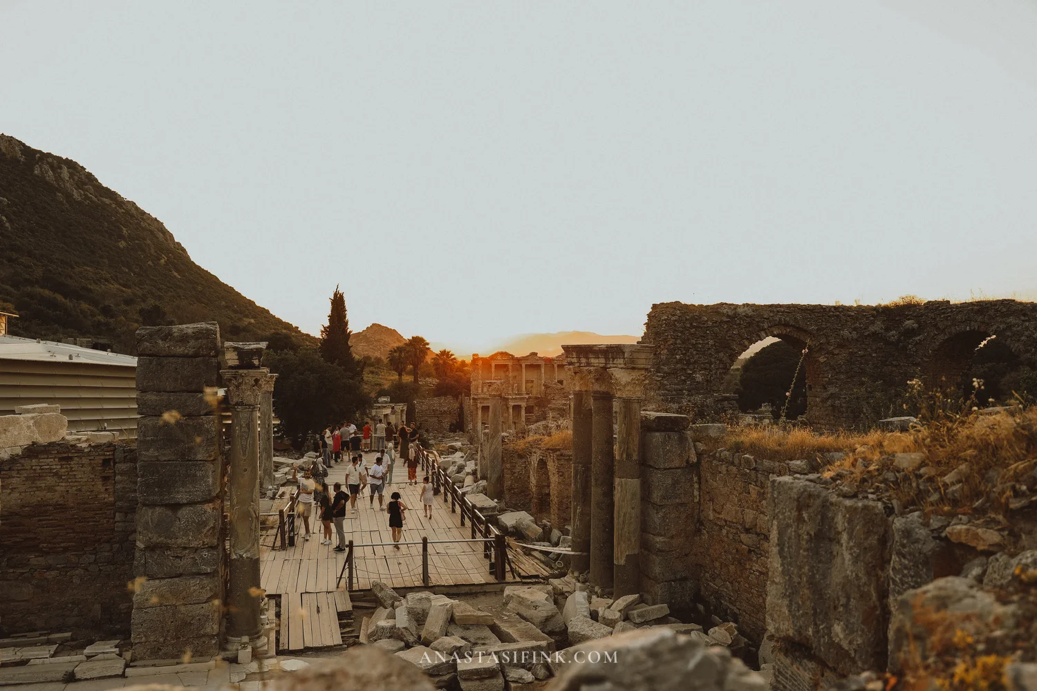 Wide boardwalk with visitors and the Library at sunset in the distance