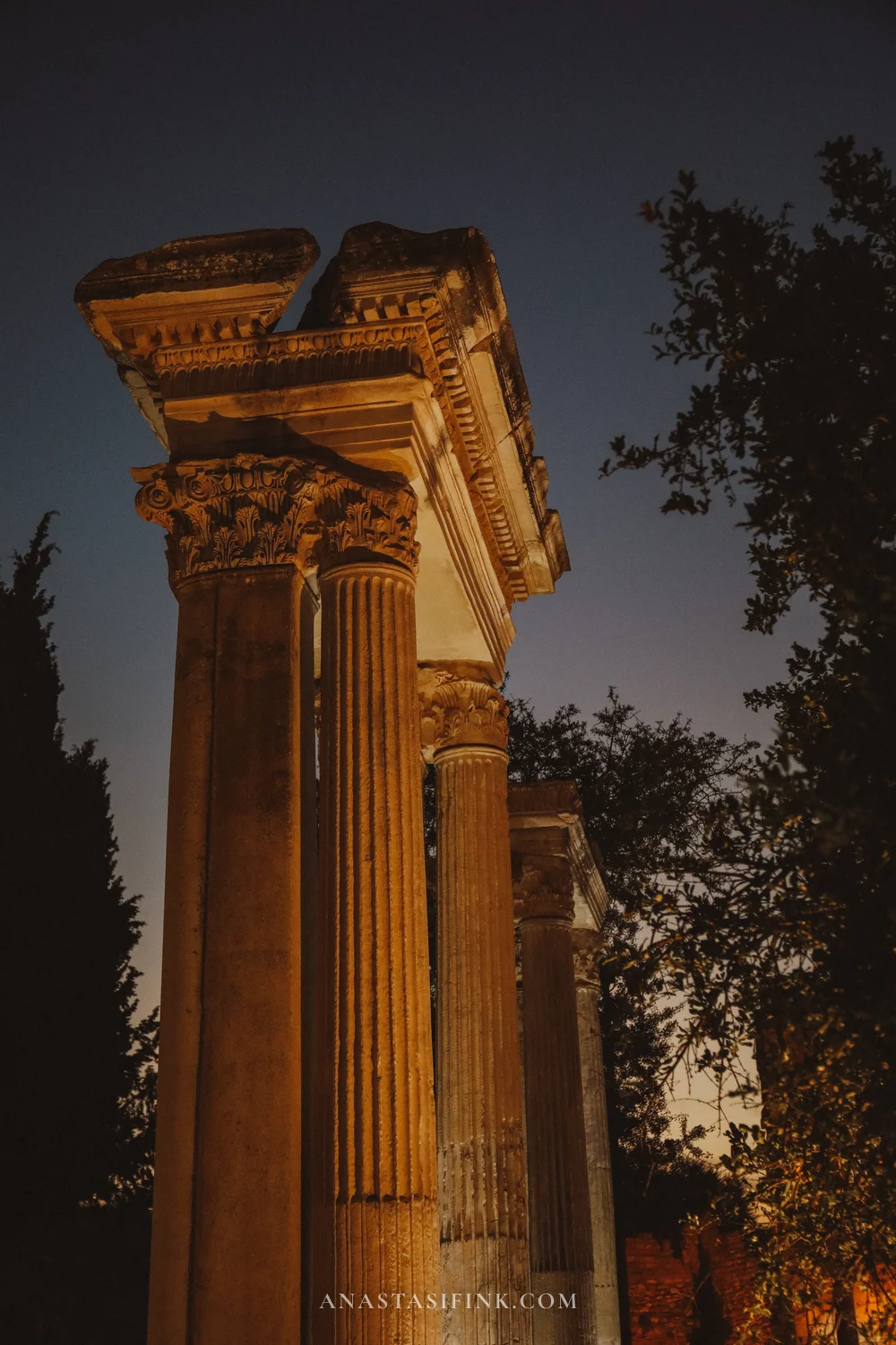 Columns against a twilight sky, trees and mountains