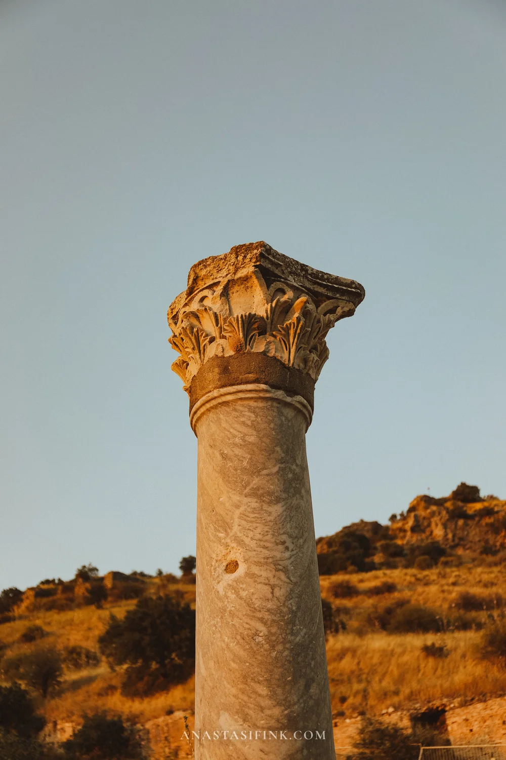 A lone Corinthian column in golden sunset light