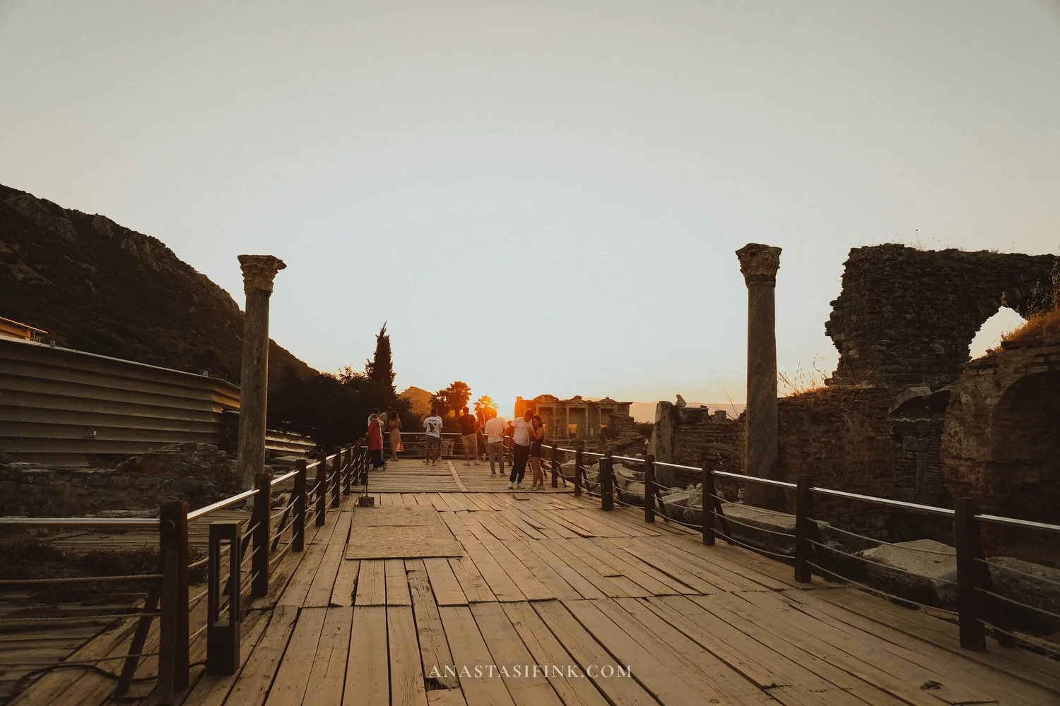 Wooden boardwalk with visitors at sunset, Library visible in the distance
