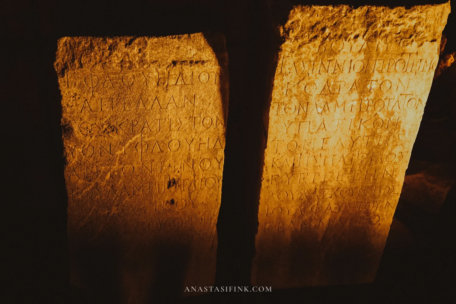 Greek inscriptions on marble slabs, illuminated at night