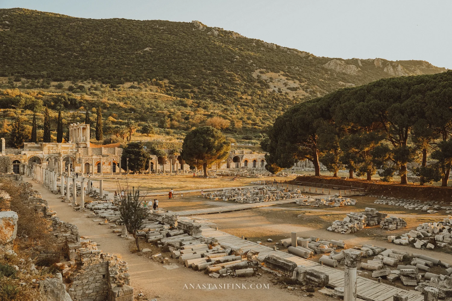 Panoramic view of the Lower Agora with colonnades, trees, and mountains behind