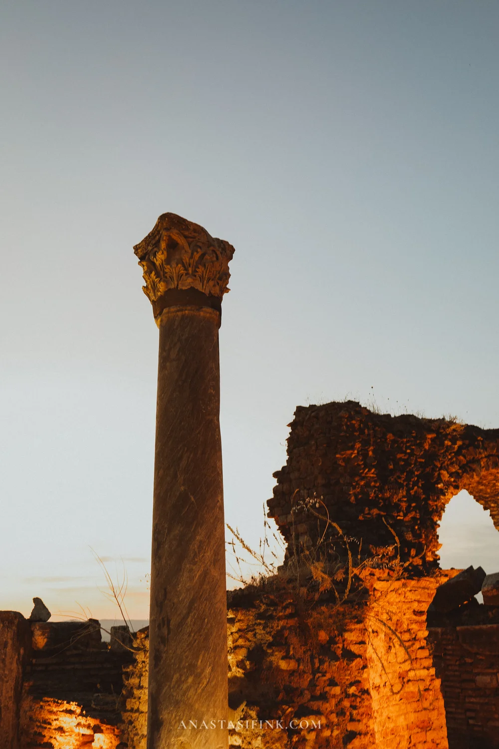 A lone column against brick ruins in evening light