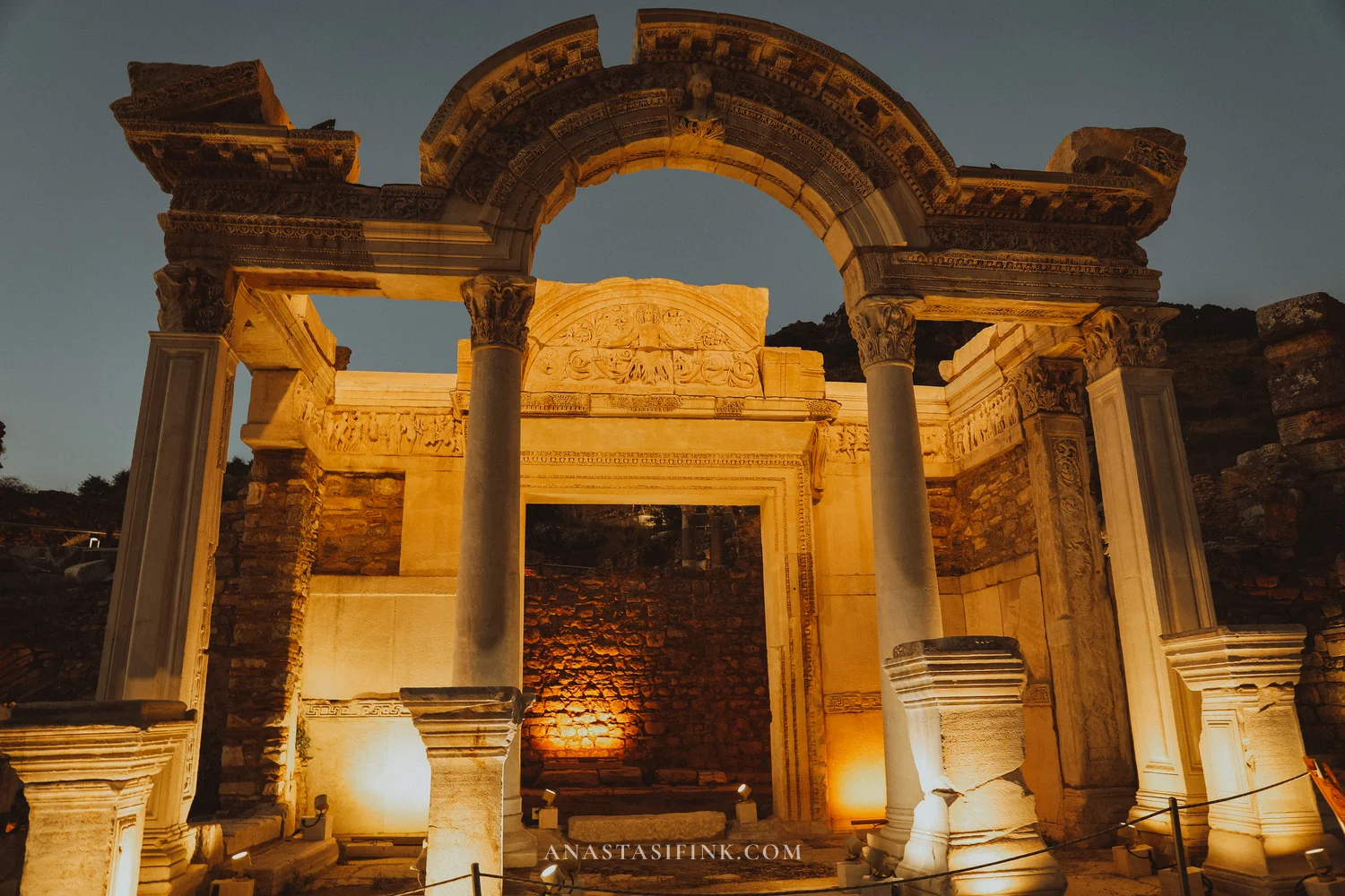Temple of Hadrian fully illuminated at night, arch and columns