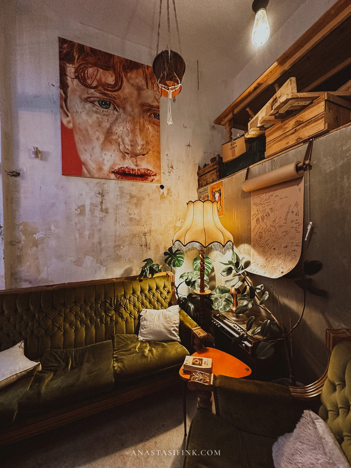 Hoi Coffee — green velvet sofa, portrait on wall, lamp