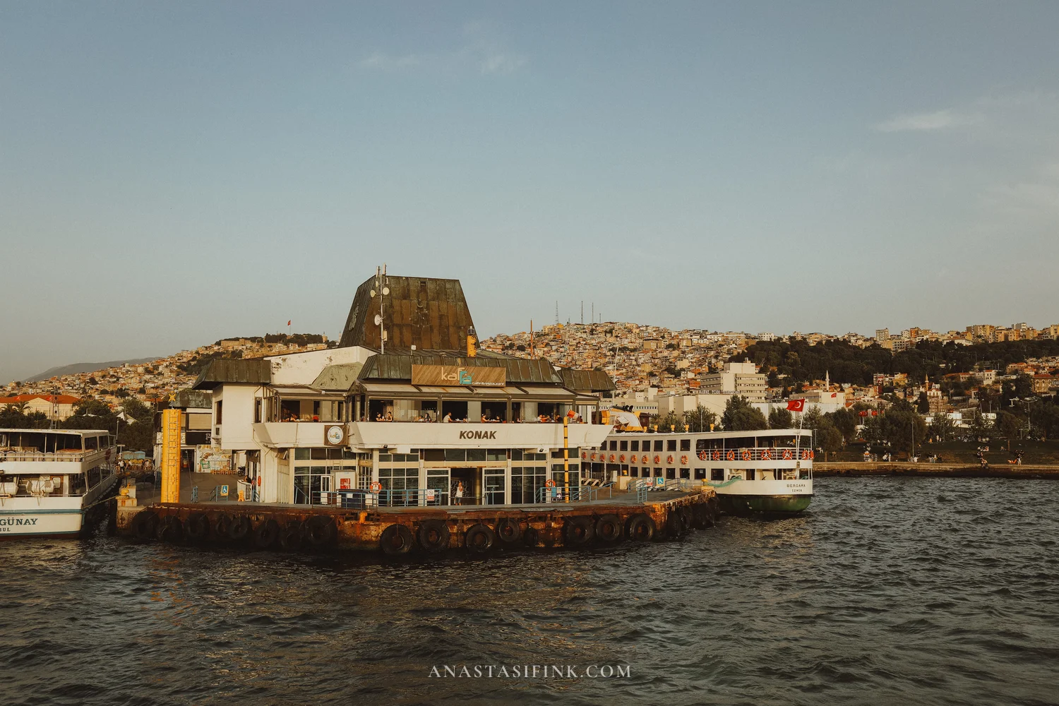 Konak ferry terminal from the water — city on hill behind