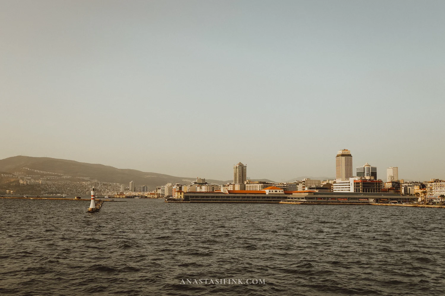 Izmir skyline from ferry — lighthouse, skyscrapers, mountains