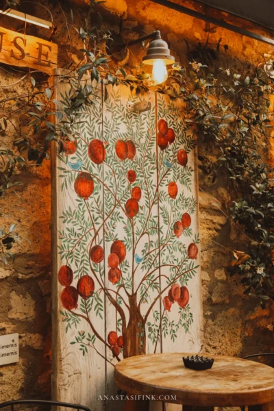 Mural with a pomegranate tree on a stone café wall