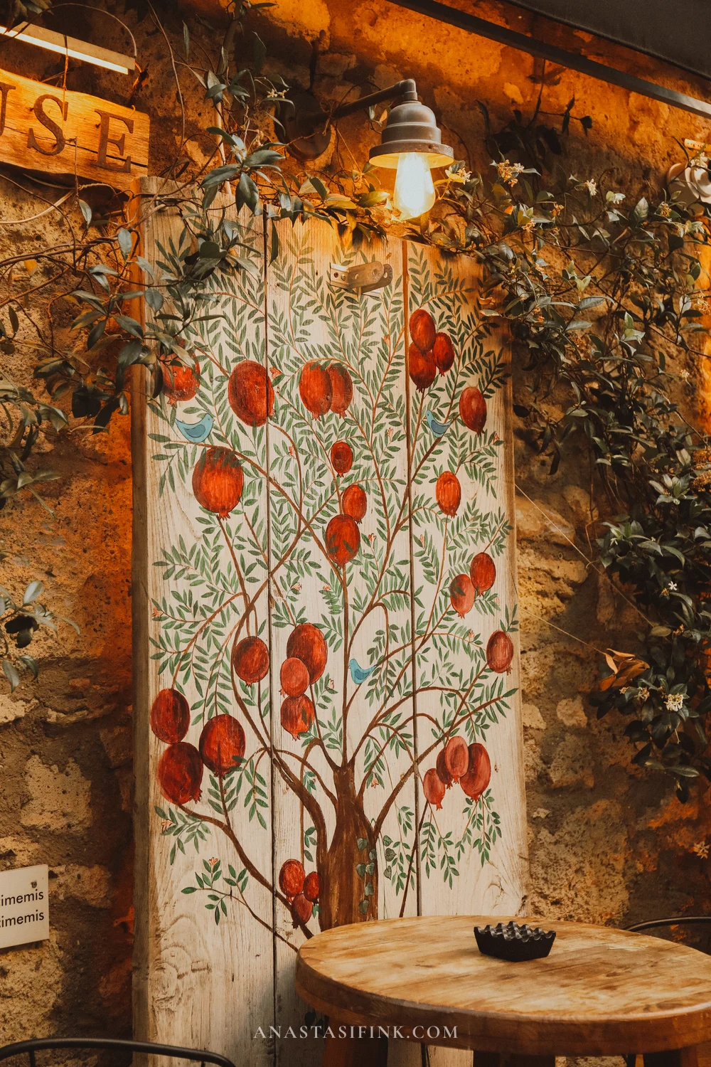 Mural with a pomegranate tree on a stone café wall