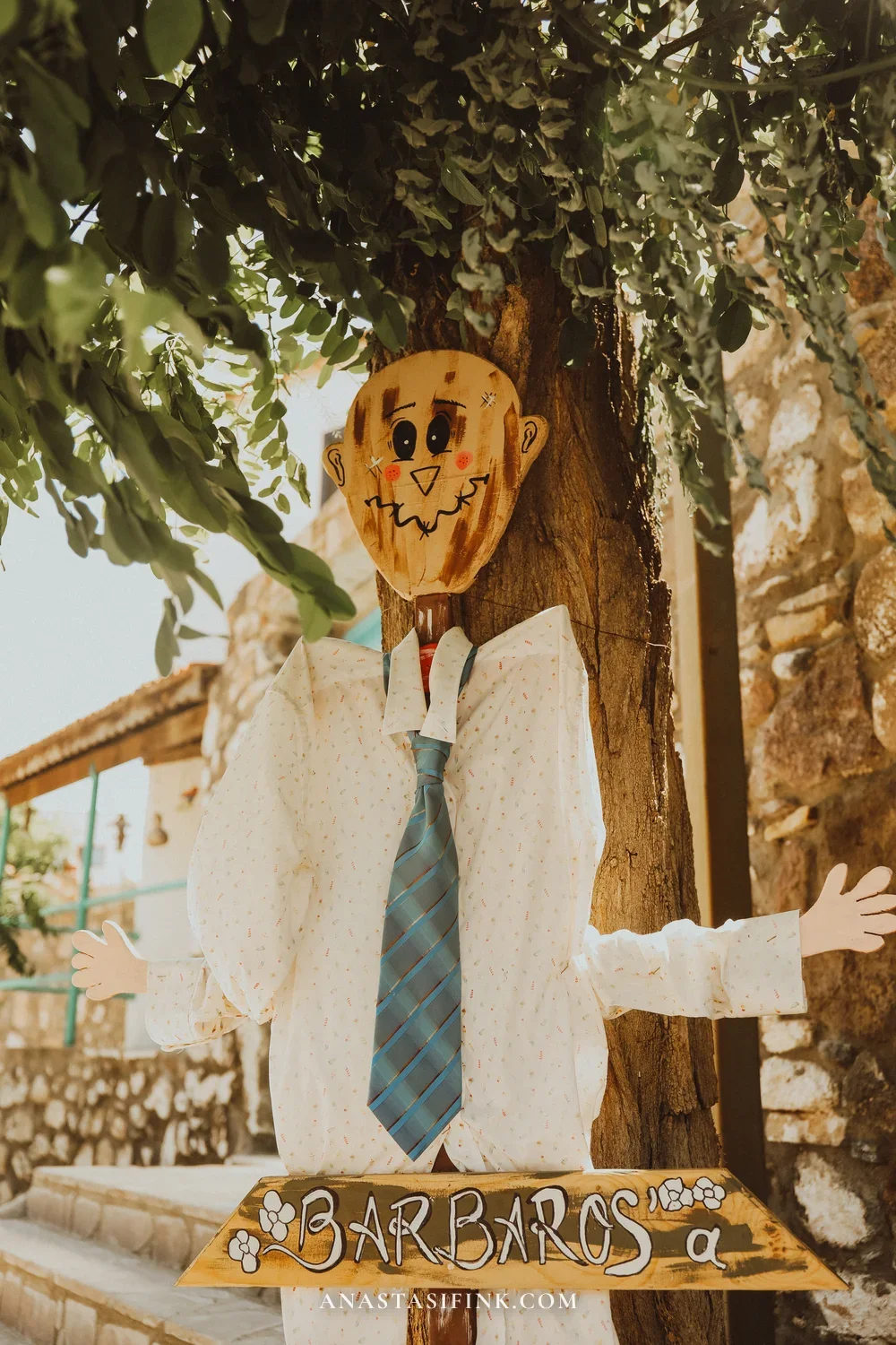 Scarecrow greeter at the entrance to Barbaros village — sign with the village name