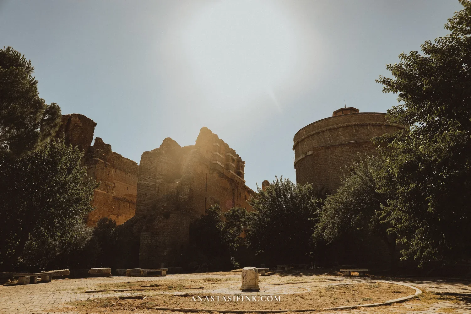 Red Basilica of Bergama in backlight — brick walls and round tower among trees