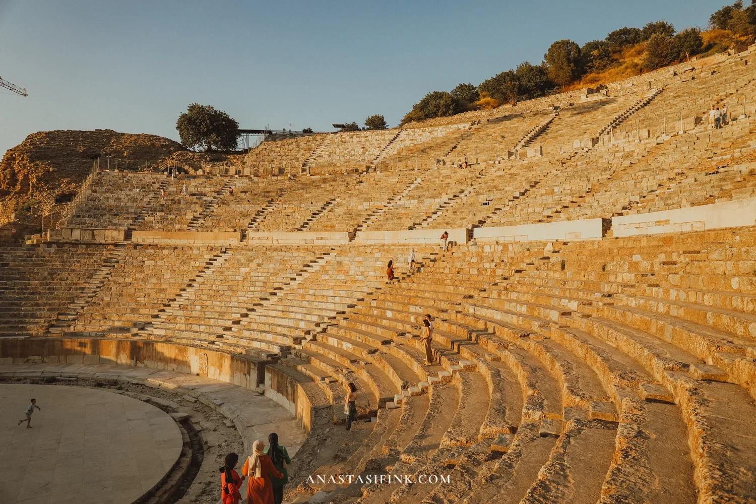 Great Theatre of Ephesus in golden hour — rows of stone seats climbing the hillside