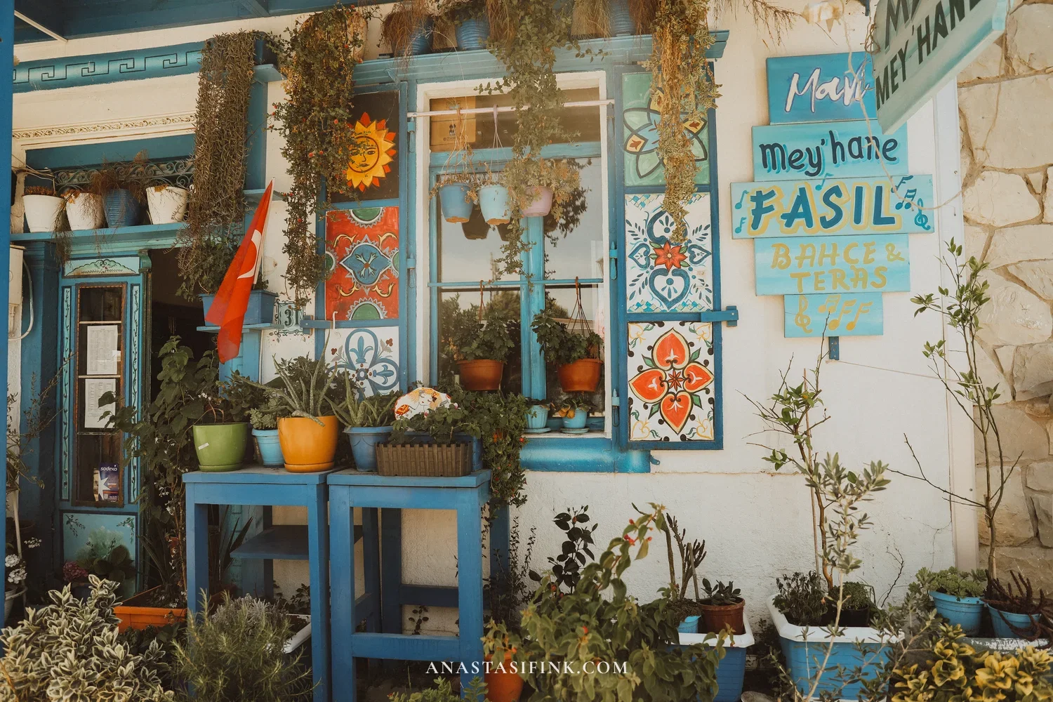 Meyhane Fasıl in Urla — blue facade with painted tiles, flower pots, and signboard