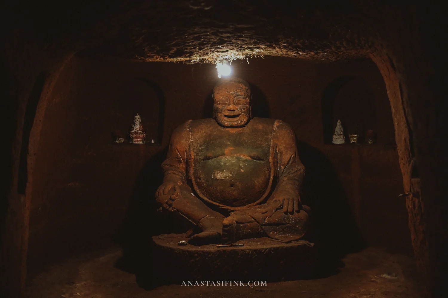 Seated Maitreya statue in the dim cave