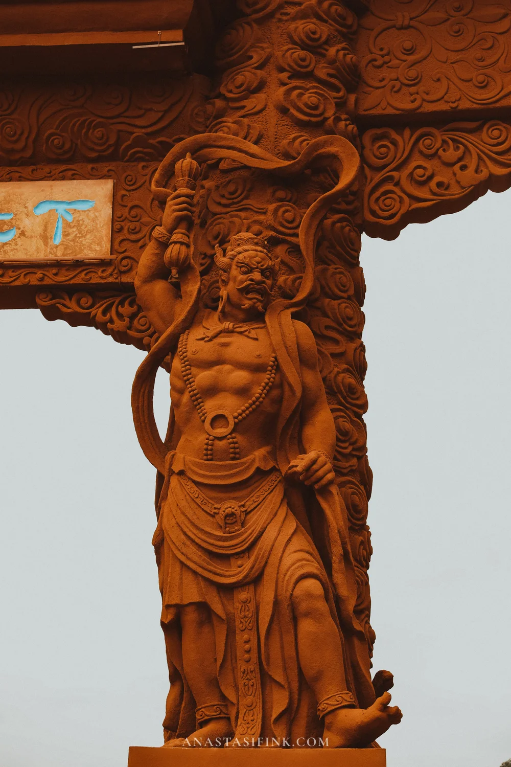 Carved guardian figure on a gate column