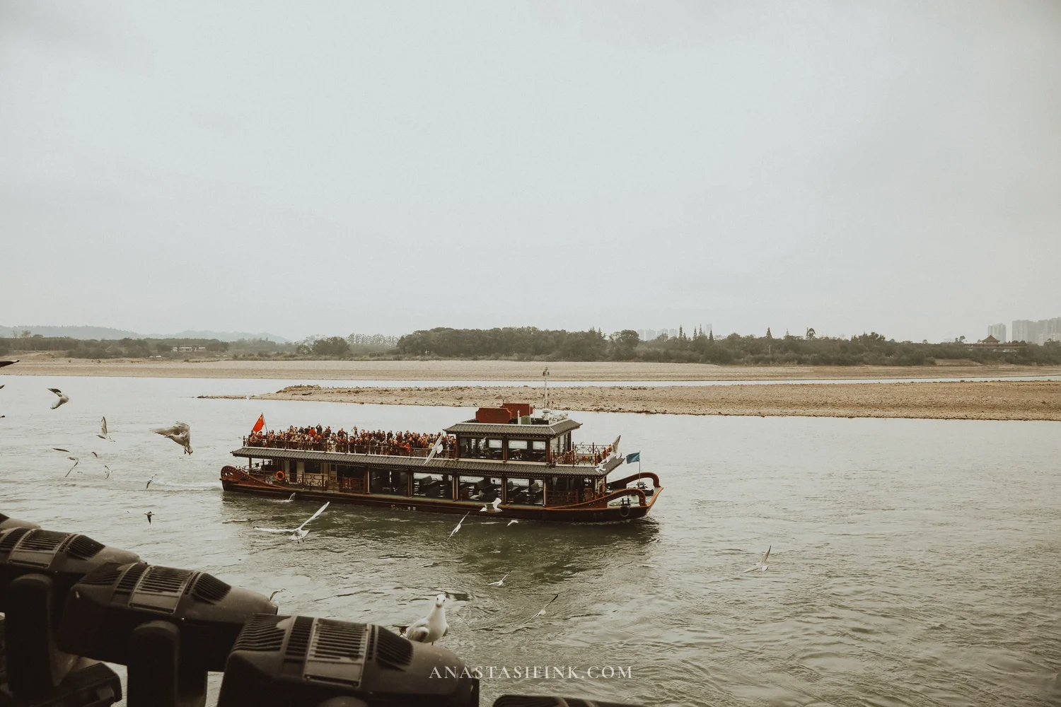 Boat with tourists and seagulls by the platform under the Buddha's feet
