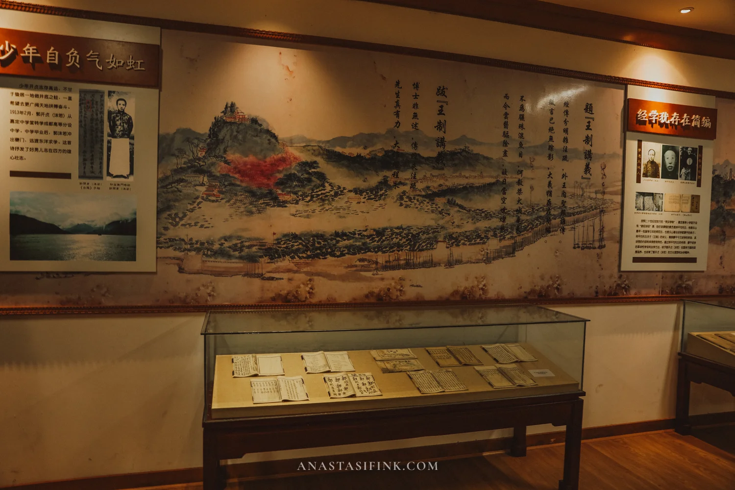 Museum display with paintings and documents behind glass