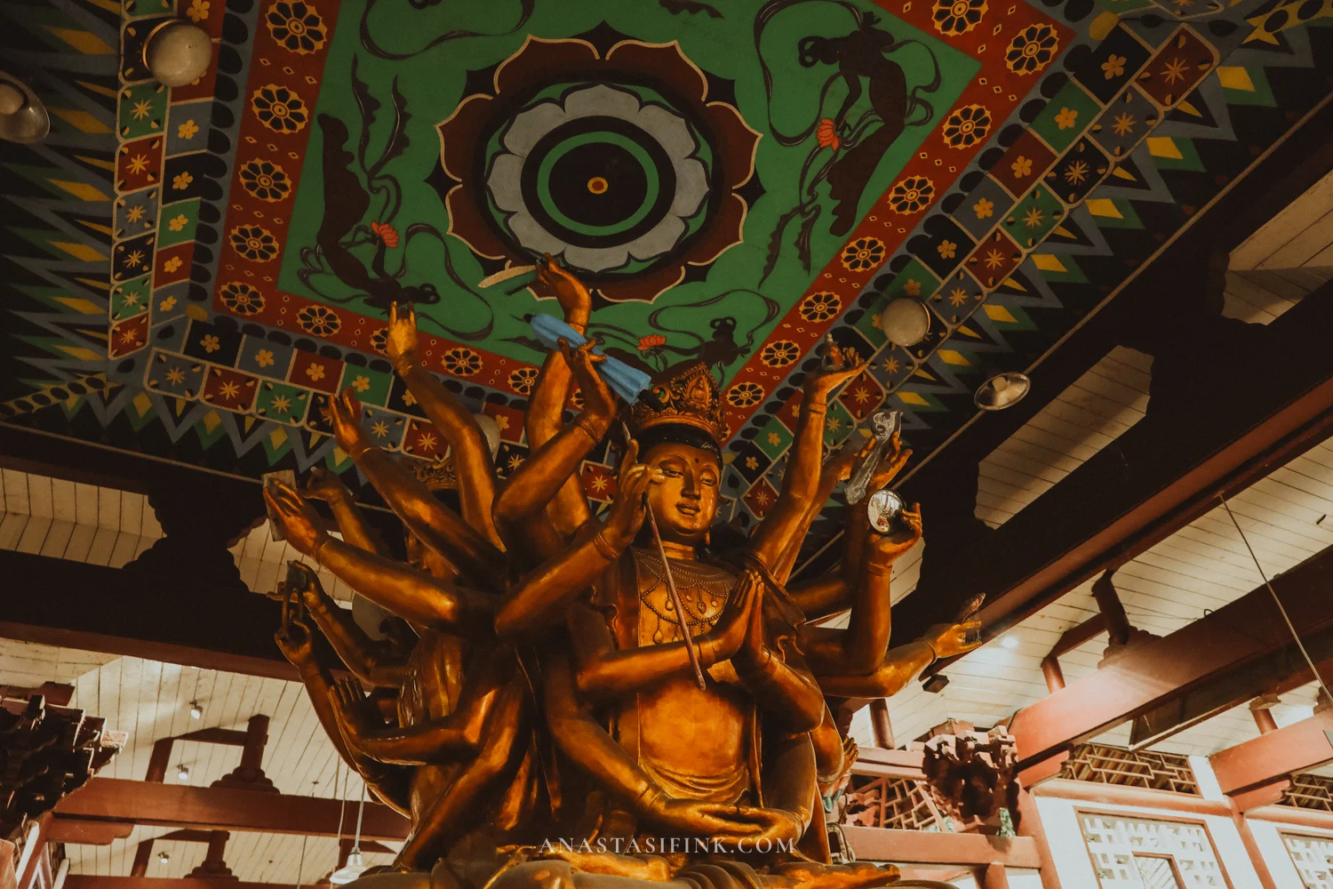 Gilded thousand-armed Guanyin under a painted ceiling