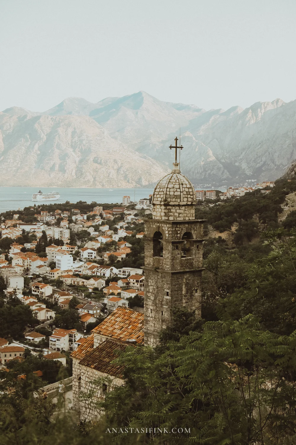 Stone bell tower of Our Lady of Remedy church above Kotor with Bay of Kotor and mountains behind