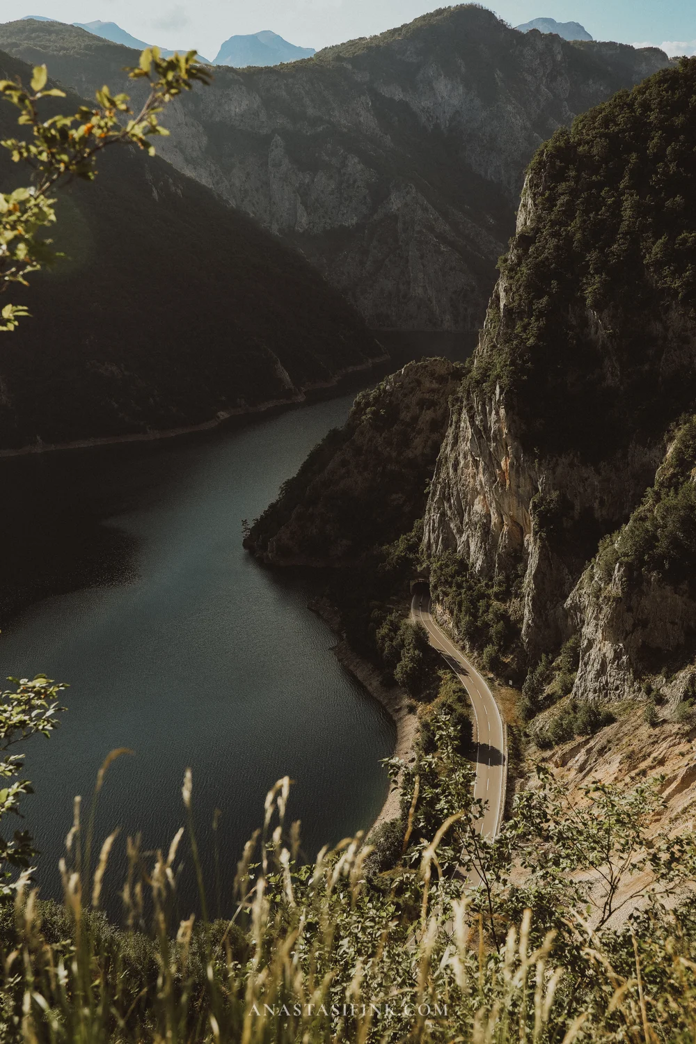 Piva Canyon road carved into the cliff above the turquoise lake, Montenegro