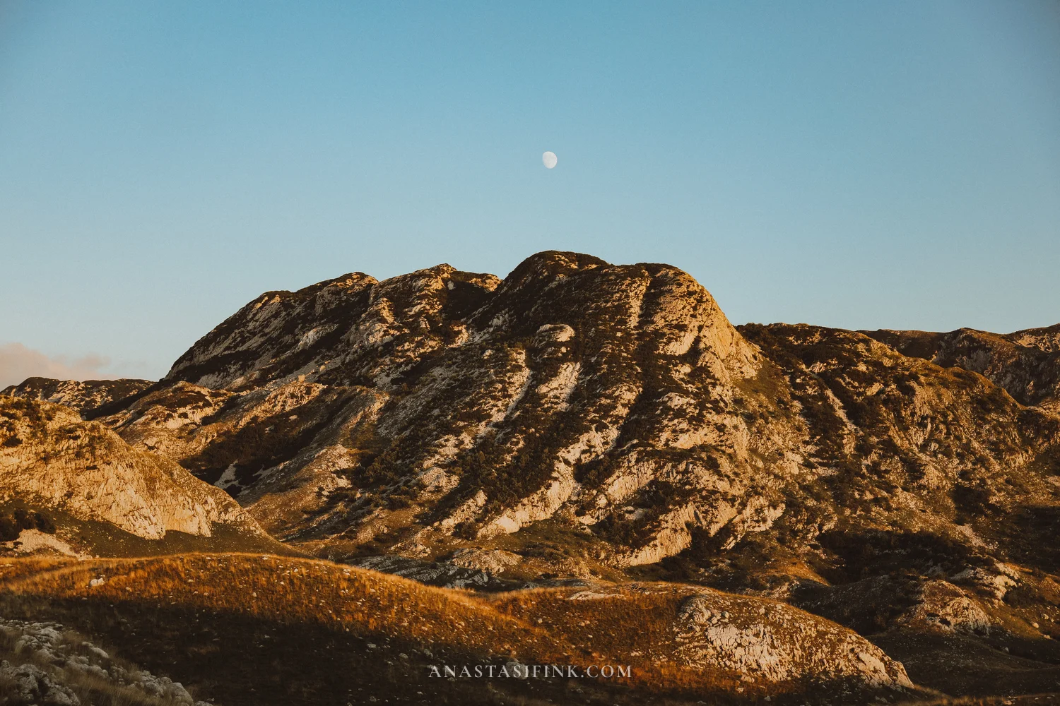 Moon rising over a sunlit rocky peak at Sedlo Pass, Durmitor, Montenegro