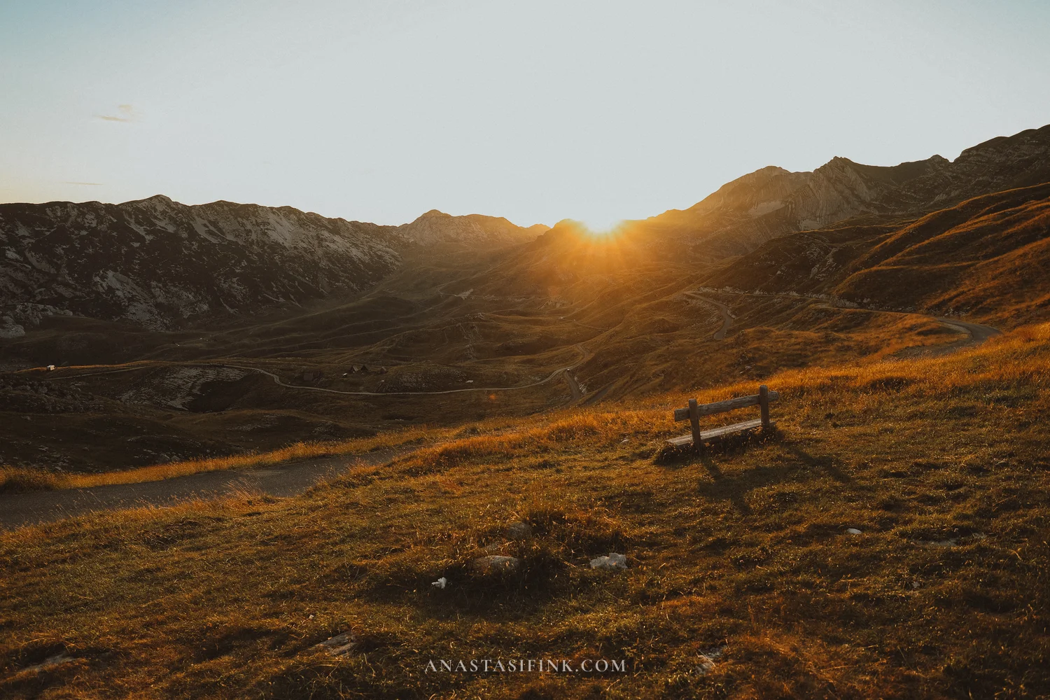 Wooden bench at Sedlo Pass with the sun setting behind the ridge, Durmitor