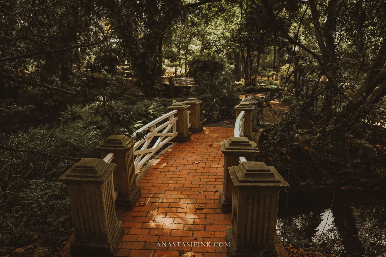 Brick bridge with white railings among trees in the Atlantic Botanical Garden of Gijón
