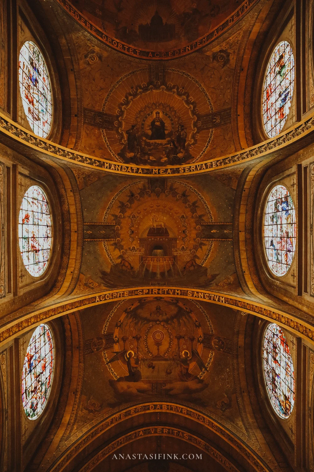 Painted vaults and round stained-glass windows along the nave of the Sagrado Corazón basilica, Gijón