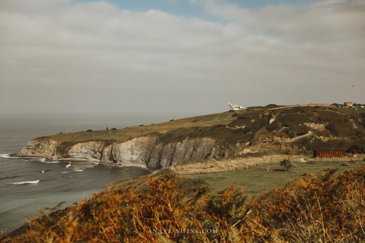 Cabo San Lorenzo cliffs with the ship-bow viewpoint of La Providencia park and a paraglider, Gijón