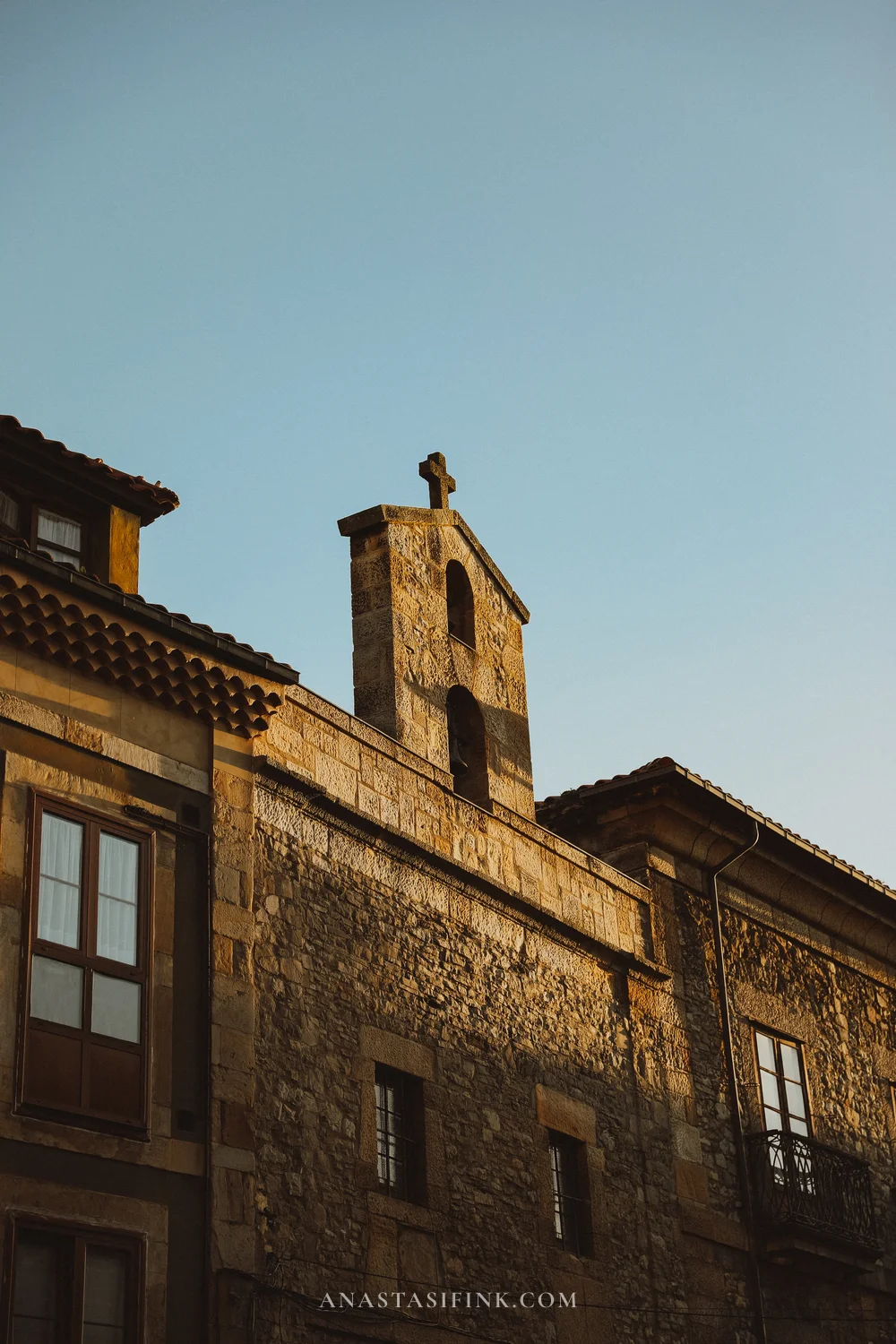 Old stone chapel with a bell gable and cross in Cimavilla, Gijón