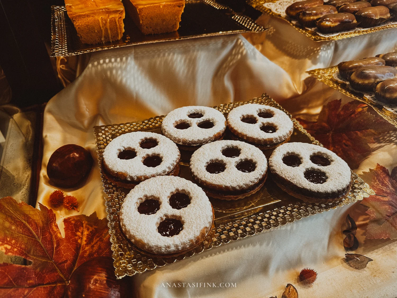 Jam-filled shortbread cookies dusted with sugar on a golden tray in a Gijón confitería
