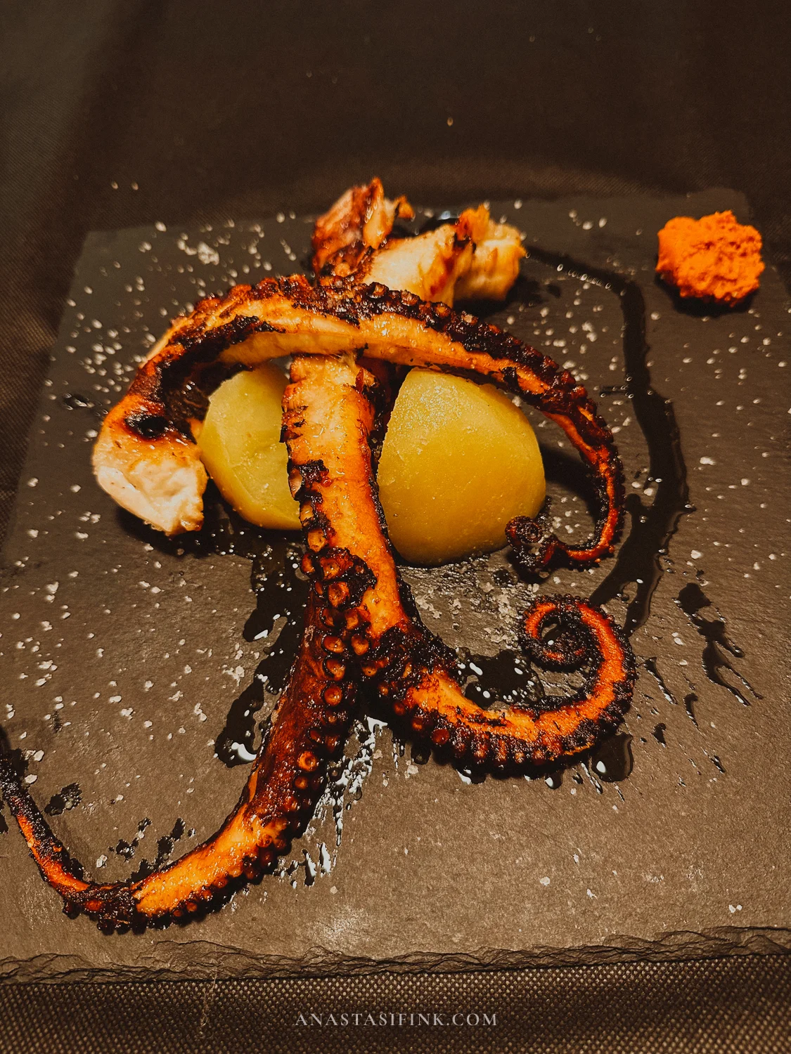 Grilled octopus tentacles with potatoes and a paprika spread on a slate at El Veleru, Gijón