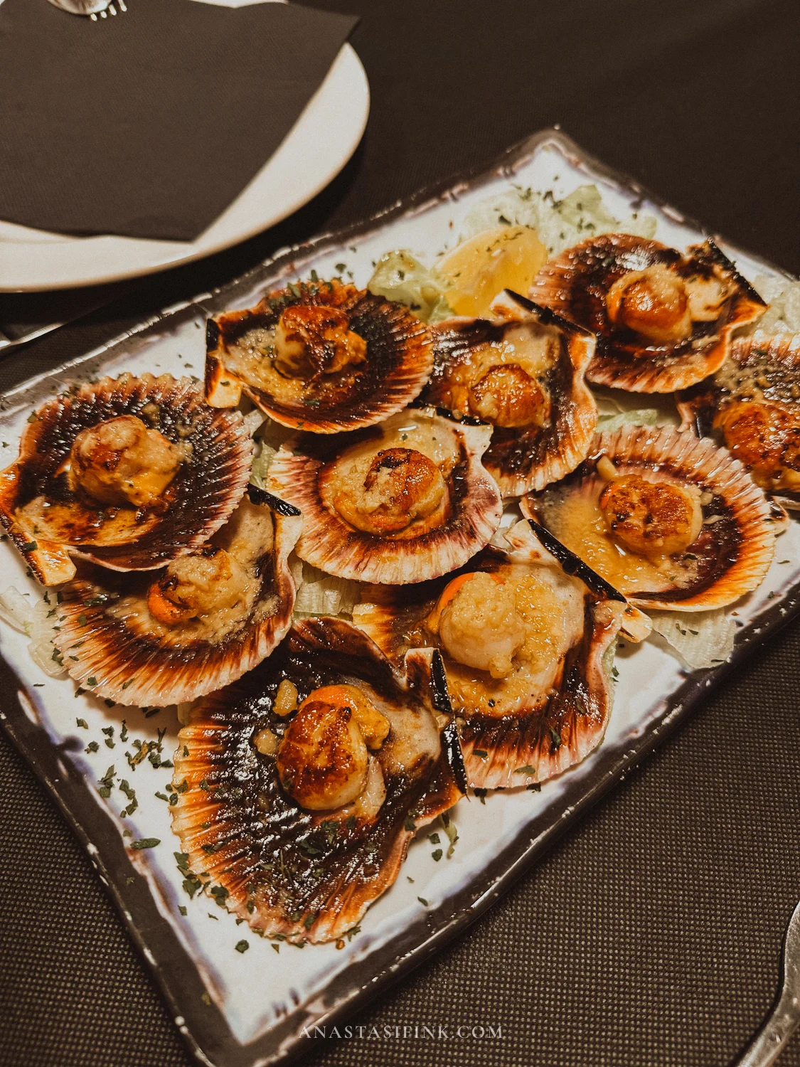 Grilled scallops in their shells on a plate at El Veleru cider house in Gijón
