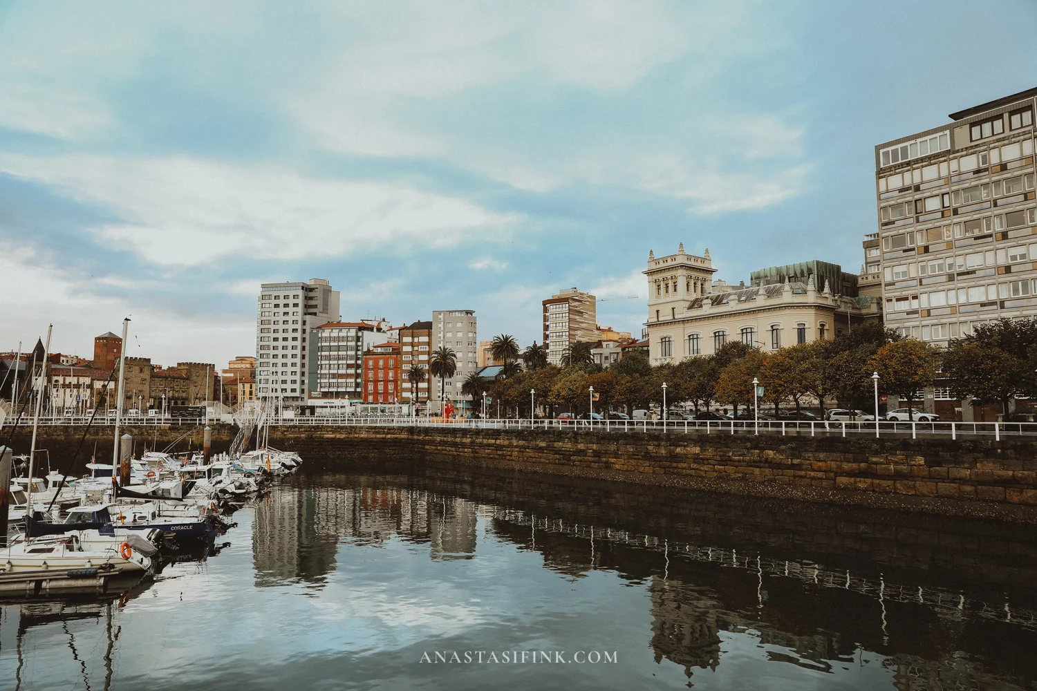 Marina of Gijón in the morning with the city centre buildings reflected in the water