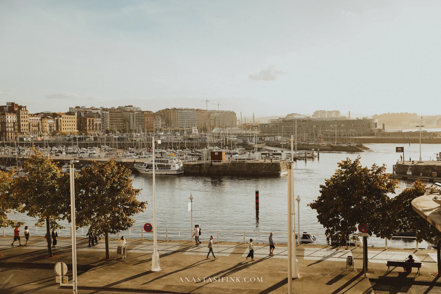 Marina promenade of Gijón in the evening with people walking along the water