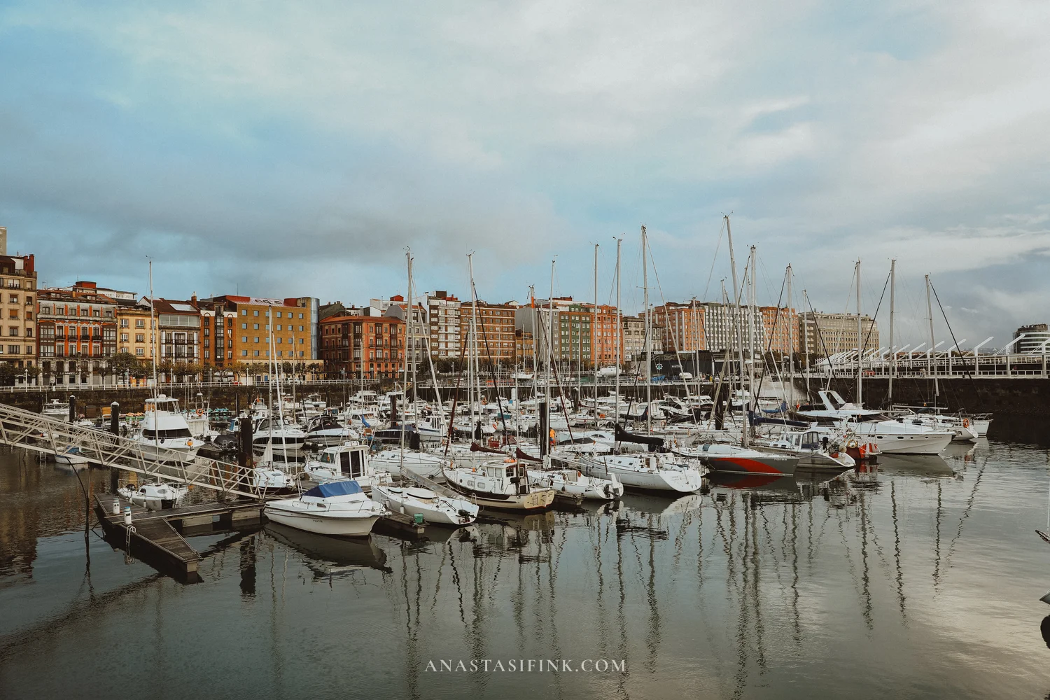 Yachts in the marina of Gijón with colourful Cimavilla houses behind