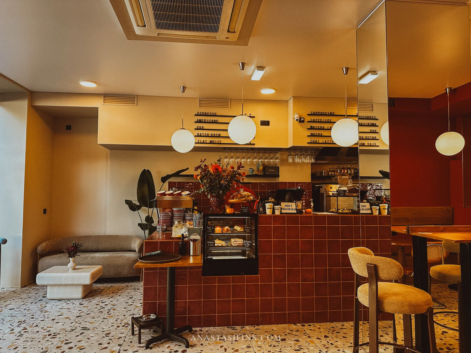 Interior of NUBO café in Gijón with a red tiled counter and terrazzo floor