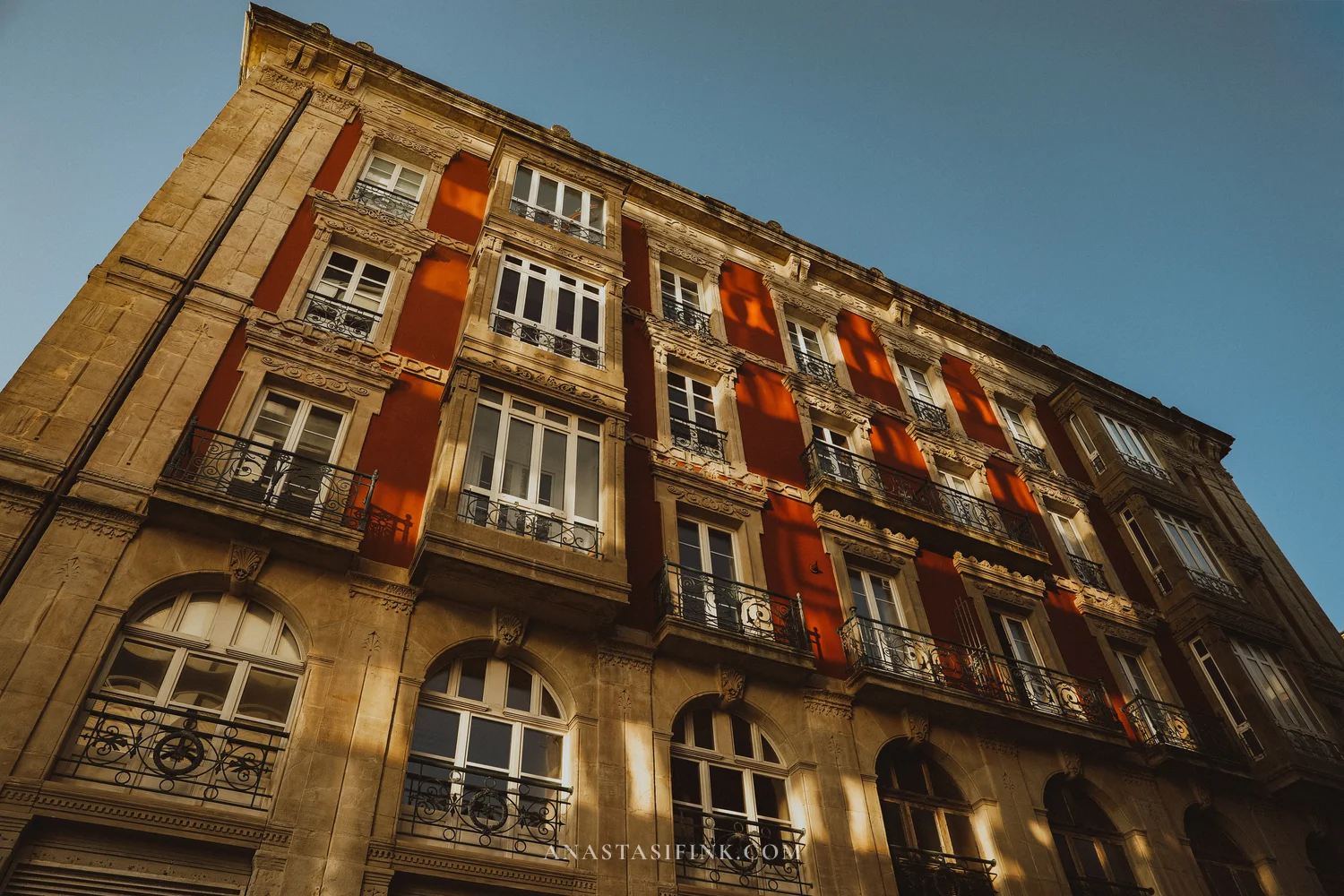 Ornate red and stone facade with iron balconies in the centre of Gijón