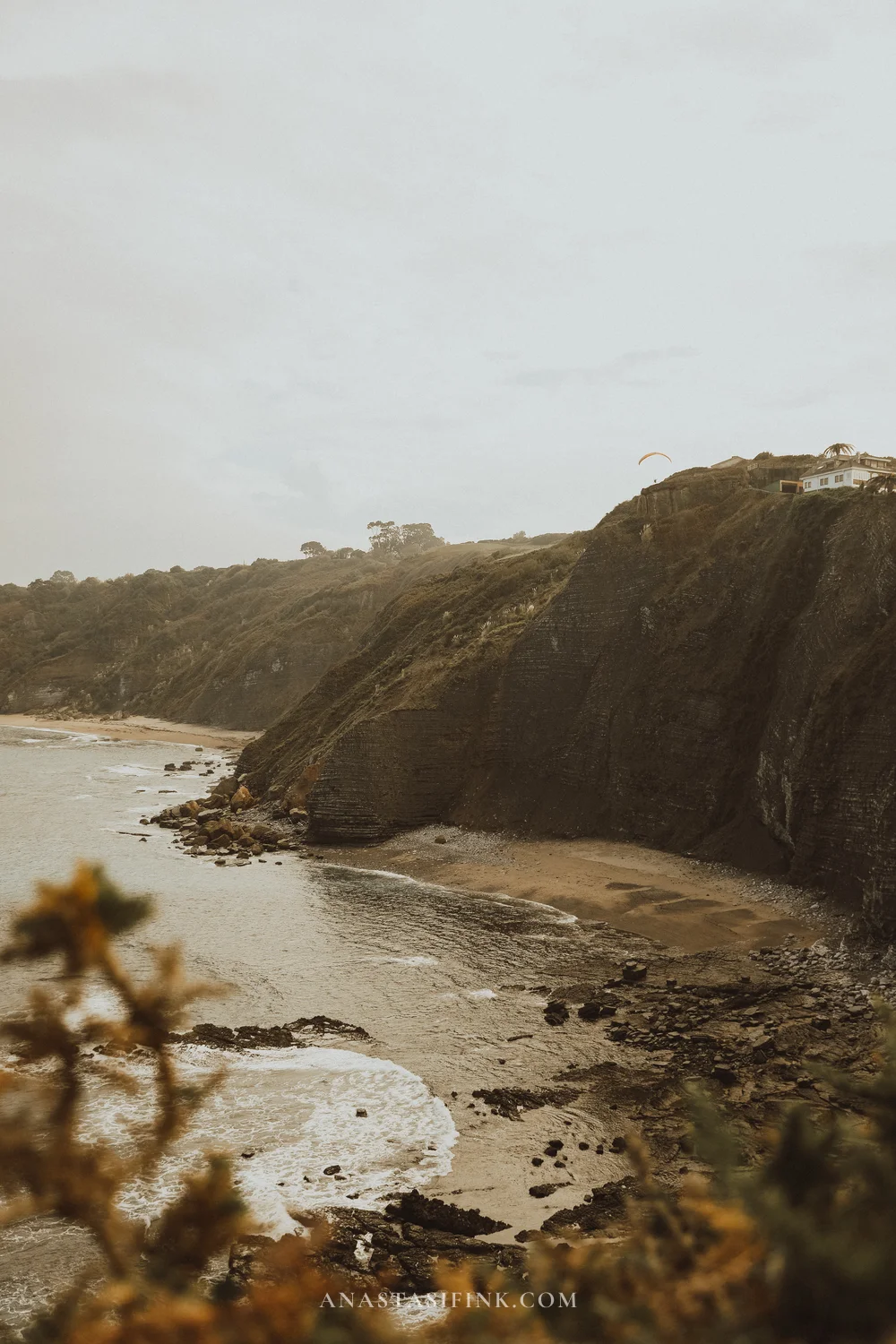 Cliffs of Playa de Serín with a paraglider in the sky, Gijón