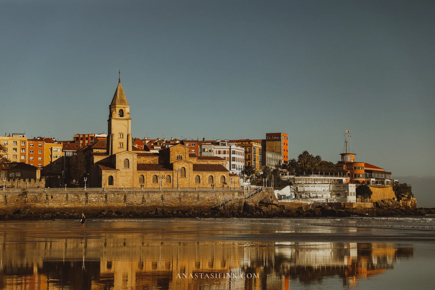 San Pedro church and Cimavilla reflected in the wet sand of San Lorenzo beach at low tide, Gijón