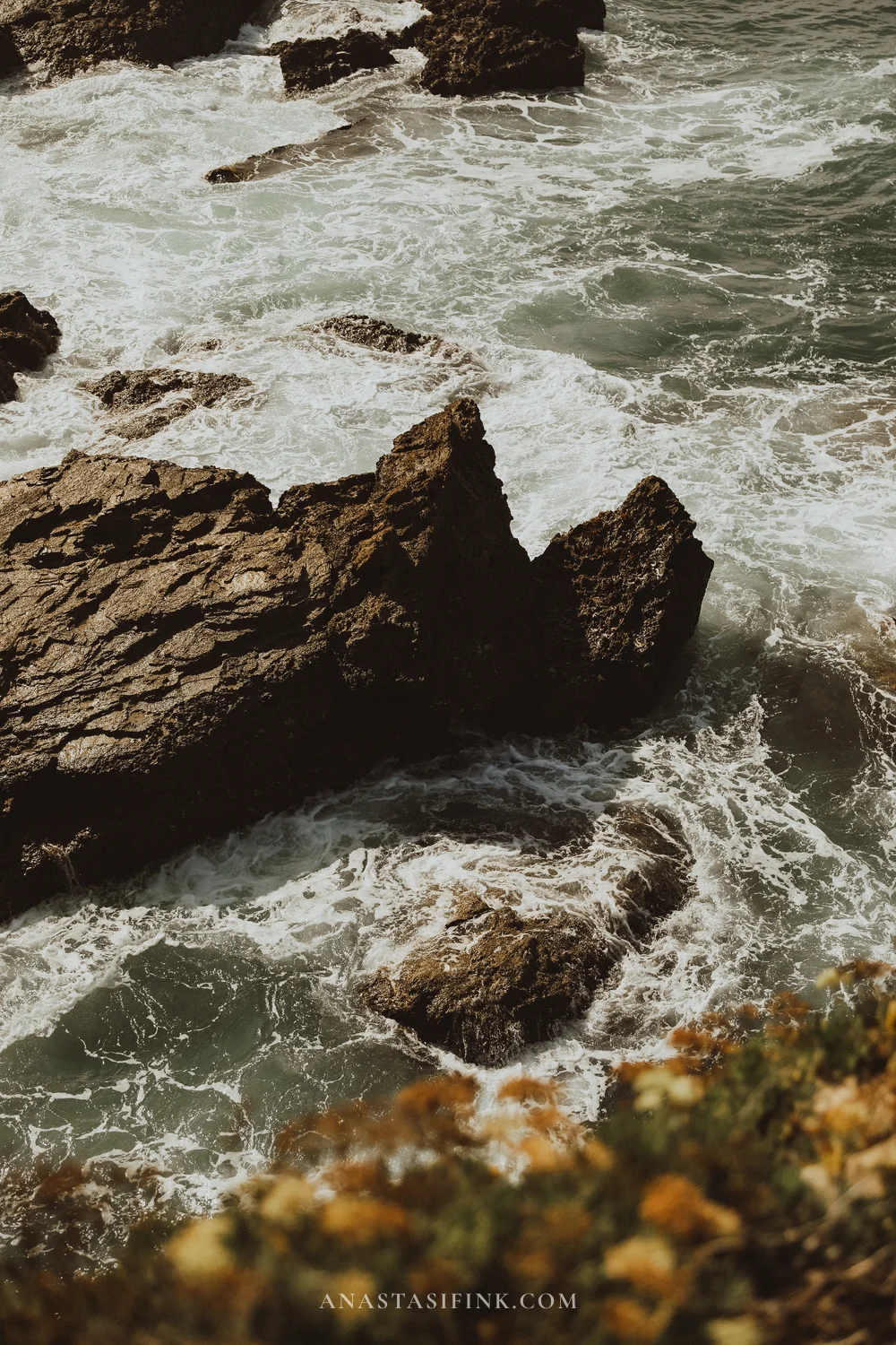 Waves foaming around dark rocks below the cliffs on the Senda del Cervigón, Gijón